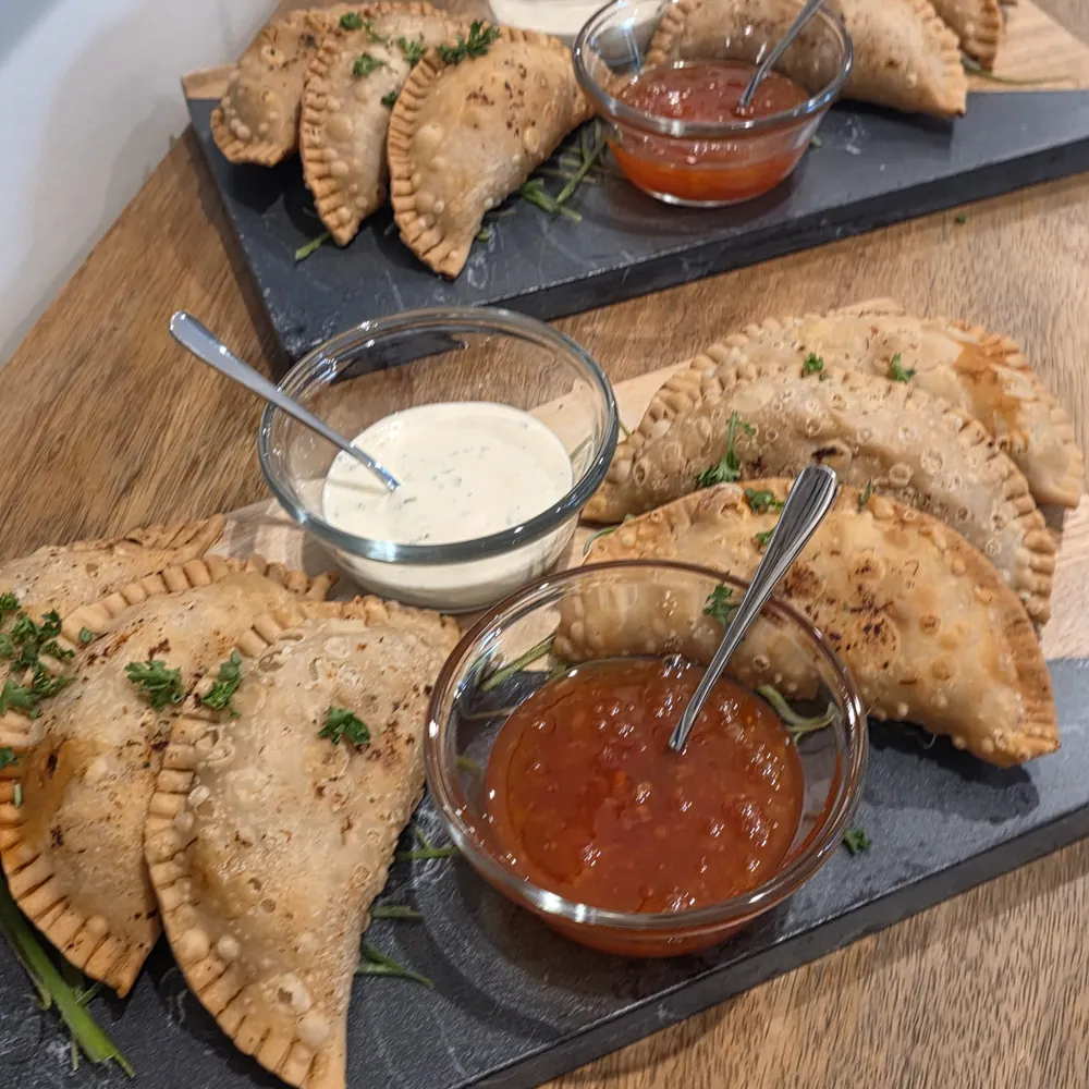 Slate boards of Big Papa’s empanadas with red and white dipping sauces
